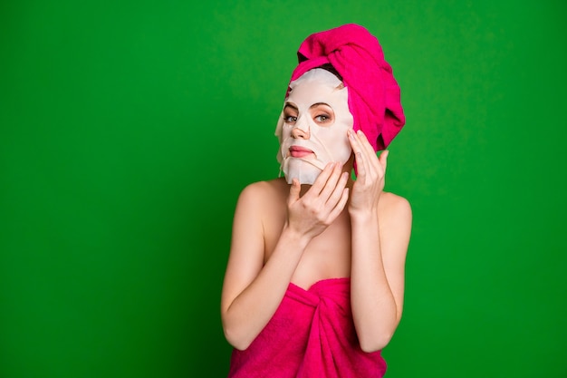 Retrato de close-up de uma moça bonita usando turbante e máscara facial se preparando isolado sobre um fundo de cor verde brilhante