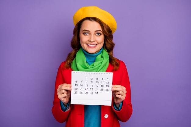 Retrato de close-up dela ela agradável atraente adorável muito charmosa alegre alegre alegre garota de cabelos ondulados segurando nas mãos calendário de papel isolado no fundo violeta lilás roxo cor pastel