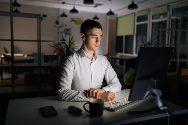 Foto retrato de comerciante masculino concentrado trabalhando olhando para um computador de mesa pensando analisando on-line