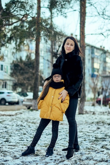 Foto retrato de comprimento completo de mãe sorridente com filha de pé ao ar livre