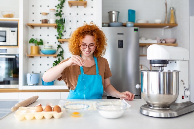 Retrato de conceito de cozimento de mulher alegre amassar massa no interior da cozinha Mulher alegre no avental se divertindo enquanto preparava a massa caseira