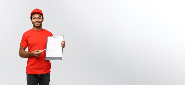 Retrato de conceito de entrega de entregador ou mensageiro afro-americano bonito mostrando um formulário de documento de confirmação para assinar isolado no espaço de cópia de fundo do estúdio cinza
