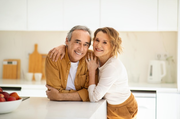 Retrato de cônjuges casados sênior felizes posando e abraçando na cozinha casal de idosos olhando e