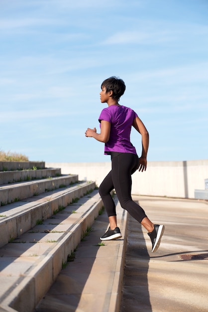 Retrato de corpo inteiro comprimento caber esportes jovem mulher correndo em passos ao ar livre