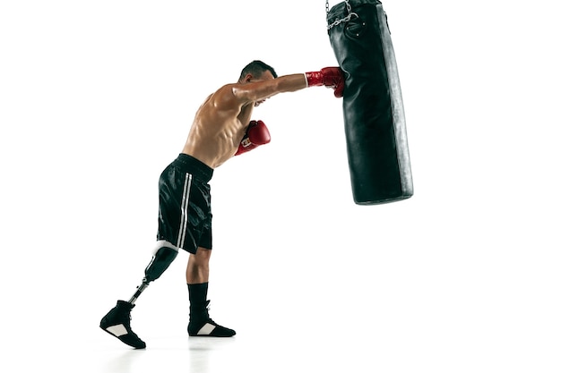 Foto retrato de corpo inteiro de esportista musculoso com perna protética, copie o espaço. boxeador masculino em luvas vermelhas, treinando e praticando. isolado na parede branca. conceito de esporte, estilo de vida saudável.