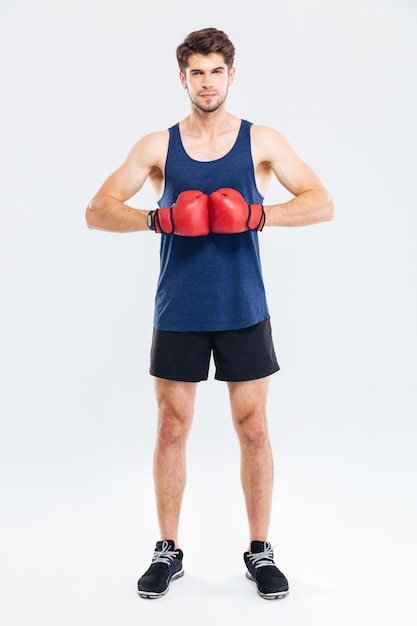 Retrato de corpo inteiro de um esportista com luvas de boxe vermelhas isolado em um fundo cinza