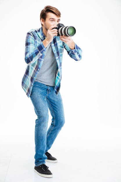 Retrato de corpo inteiro de um fotógrafo do sexo masculino fazendo fotos em uma câmera fotográfica isolada em um fundo branco