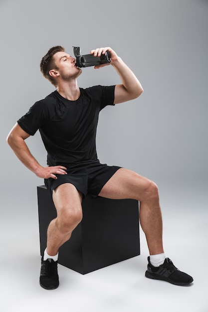 Retrato de corpo inteiro de um jovem desportista sentado em um quarteirão