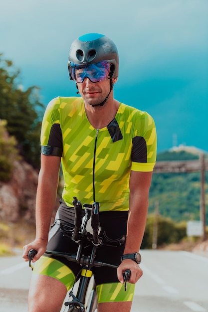 Retrato de corpo inteiro de um triatleta ativo em roupas esportivas e com um capacete protetor andando de bicicleta. Foco seletivo.