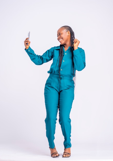 Retrato de corpo inteiro de uma jovem africana feliz usando um telefone inteligente isolado em um fundo branco