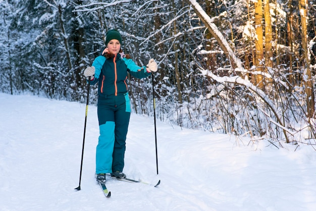 Retrato de corpo inteiro de uma jovem bonita e ativa esquiando na floresta de neve de inverno