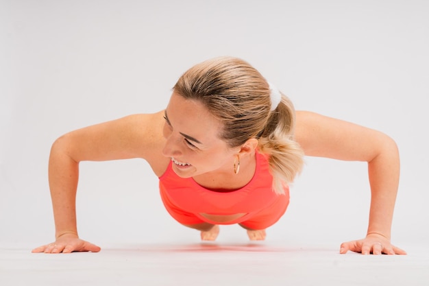 Retrato de corpo inteiro de uma jovem sorridente em roupas esportivas isoladas sobre o fundo do estúdio