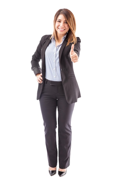 Retrato de corpo inteiro de uma linda mulher de terno dando um polegar para cima e convidando as pessoas a gostar de sua página de negócios