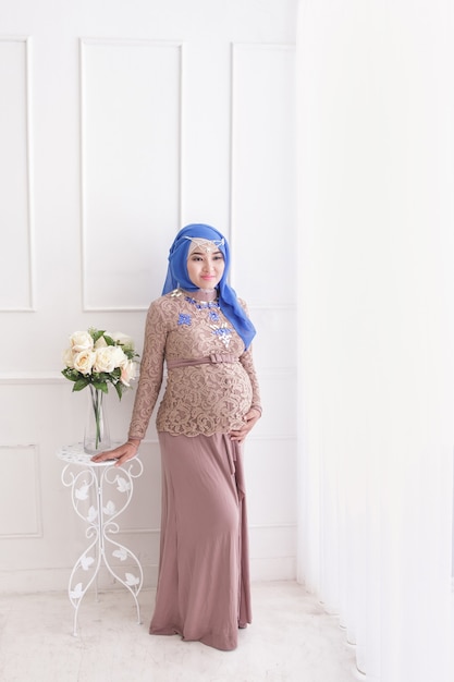 Retrato de corpo inteiro de uma mulher grávida asiática usando hijab