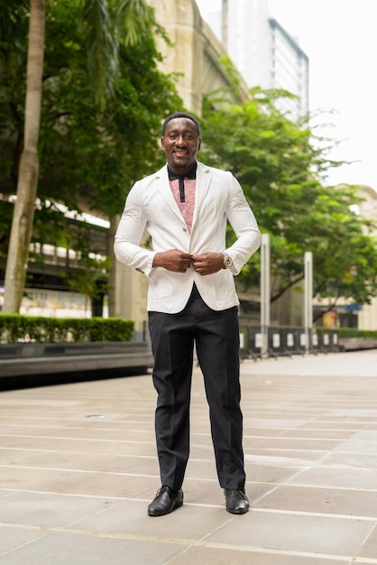 Retrato de corpo inteiro do belo empresário africano na cidade sorrindo