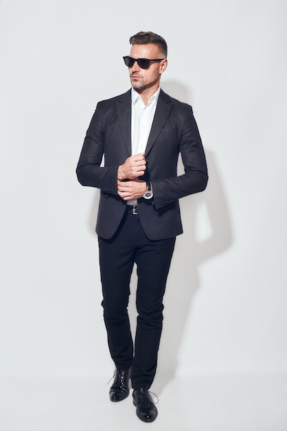 Retrato de corpo inteiro elegante e bem-sucedido de um empresário barbudo de boa aparência em terno clássico e