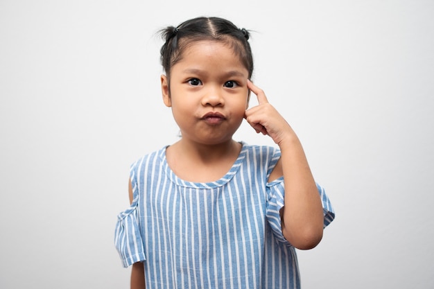 Retrato de criança asiática de 5 anos e para pentear o cabelo e colocar o dedo indicador na cabeça e fazer pose pensativa