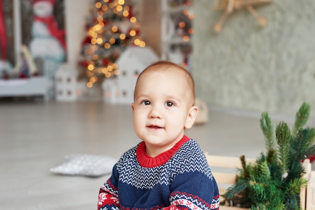 Retrato de criança bebê com a árvore de Natal. Criança bonita de Natal. Conceito de férias em família. As crianças brincam na sala. Natal no quarto das crianças.