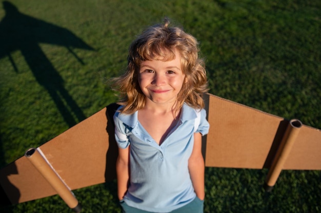 Retrato de criança com asas de mochila Criança brincando de aviador piloto e sonhos ao ar livre no parque Criança sorridente sonhando com férias de verão e viagens