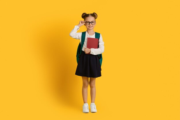 Retrato de criança da escola de uma menina bonitinha com mochila e pastas de trabalho