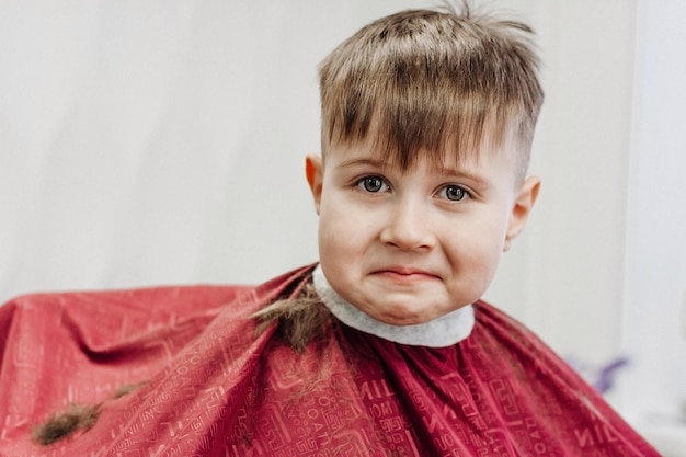 Retrato de criança do sexo masculino na barbearia para cortar o cabelo Garotinho corta o cabelo em um salão de cabeleireiro