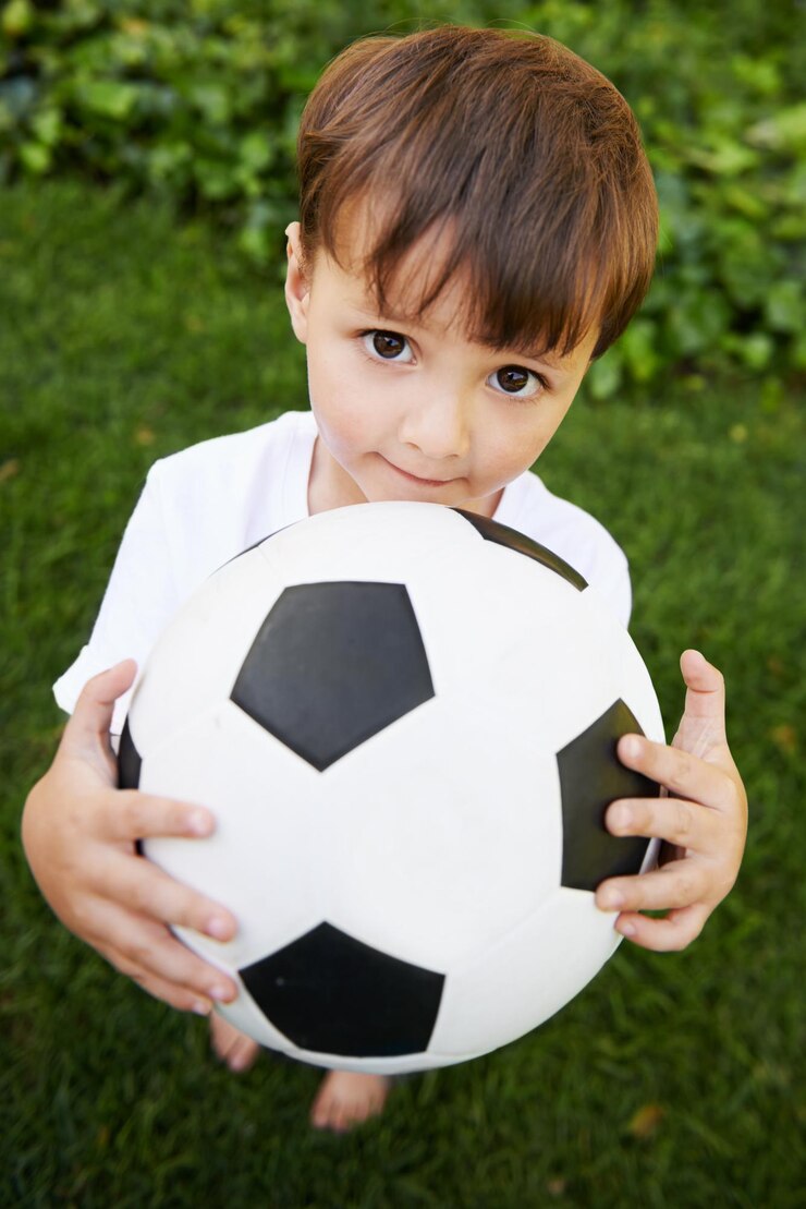Foto retrato de criança e brincar com futebol no jardim para diversão desenvolvimento saudável e infantil no brasil closeup doce e jovem menino com bola de futebol para o jogo da tarde ou exercício no quintal ou parque