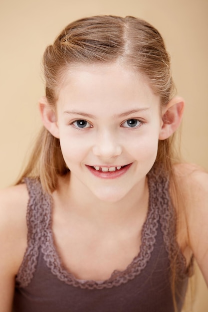 Retrato de criança e sorriso em estúdio para a confiança da juventude em fundo castanho como mockup espaço inocência ou relaxar modelo de pessoa feminina e rosto de jovem estudante para humor positivo fofo ou natural