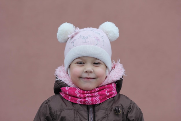 Foto retrato de criança em pano quente na temporada de inverno, olhando de lado no fundo roxo