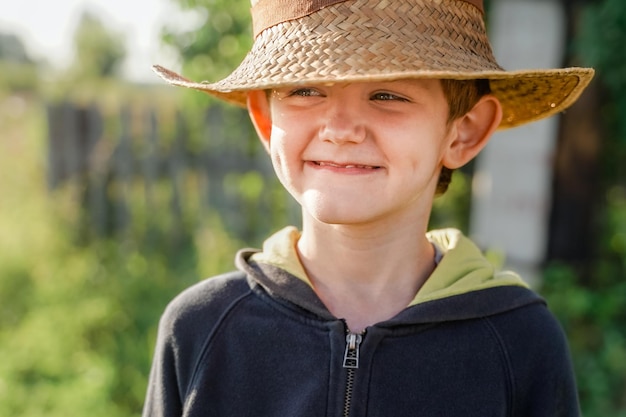 Retrato de criança em um chapéu de palha na aldeia no verão