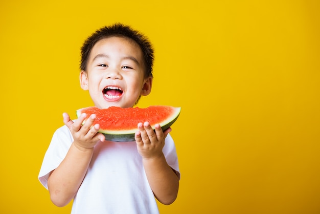 Retrato de criança menino sorrindo segurando melancia fresca para comer