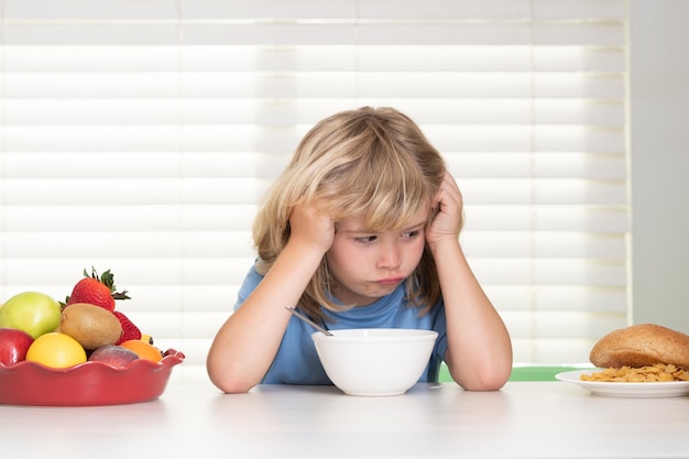 Retrato de criança sem apetite Conceito de perda de apetite Garoto pré-adolescente na cozinha na mesa comendo vegetais e frutas durante o jantar Almoço Prato de vegetais de comida saudável para crianças