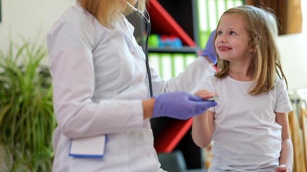 Retrato de criança sorridente na consulta com o médico pediatra pequena menina tocando