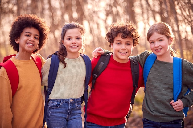 Retrato de crianças com mochilas escolares ao ar livre com os braços em volta um do outro