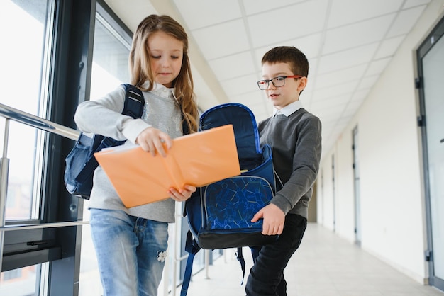 Retrato de crianças de escola sorridentes no corredor da escola com livros