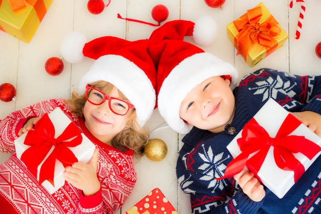 Retrato de crianças felizes com caixas de presente de Natal e decorações. Duas crianças se divertindo em casa