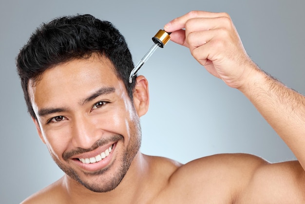 Retrato de cuidados com a pele de um homem ou soro em estúdio para tratamento óleo de abacate ou produto anti-envelhecimento Pipeta ou sorriso de pessoa masculina para rotina de pele com líquido de vitamina C ou dermatologia em fundo cinza