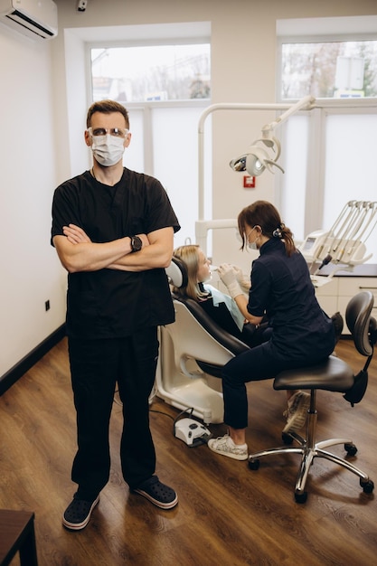 Retrato de dentista em pé com os braços cruzados na clínica