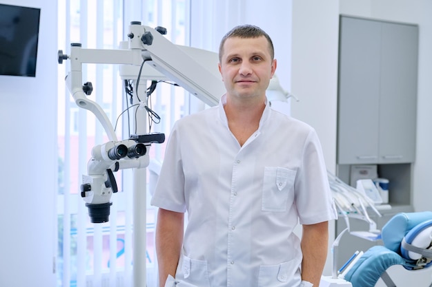 Retrato de dentista masculino feliz e amigável, médico profissional sorridente, olhando para a câmera na clínica odontológica