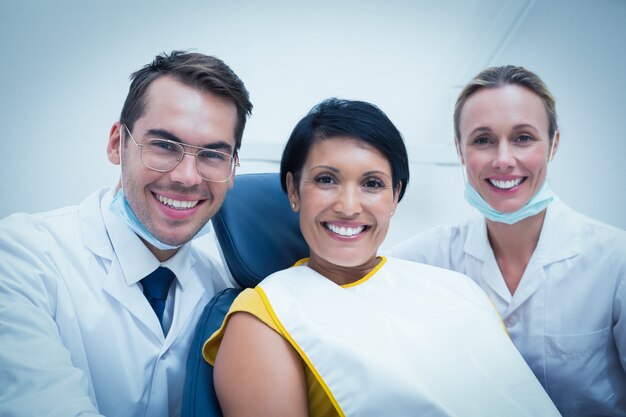 Retrato de dentista sorrateiro e assistente com paciente