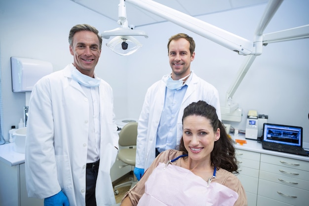 Retrato de dentistas sorridentes e paciente do sexo feminino