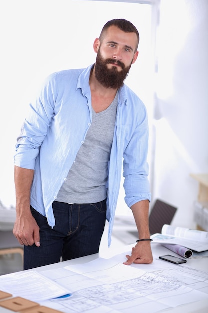 Retrato de designer masculino com plantas na mesa no escritório, isolado