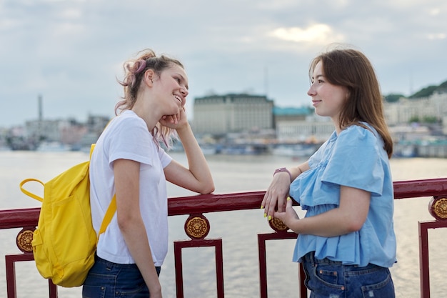 Retrato de dois amigos adolescentes andando e conversando na ponte pedonal num dia ensolarado de verão. amizade, estilo de vida, juventude, adolescentes