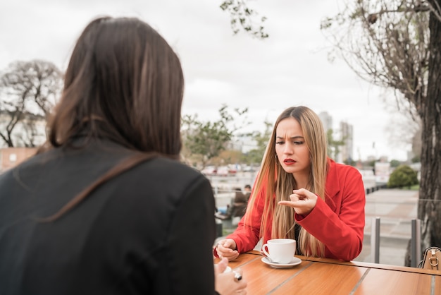 Foto retrato de dois amigos zangados, conversando séria e discutindo enquanto está sentado em uma cafeteria