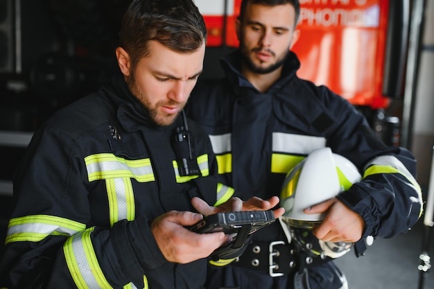 Retrato de dois bombeiros em operação de combate a incêndio bombeiro em roupas de proteção e capacete usando computador tablet em ação de combate