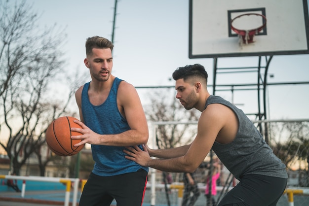 Retrato de dois jovens amigos jogando basquete e se divertindo na quadra ao ar livre. Conceito de esportes.