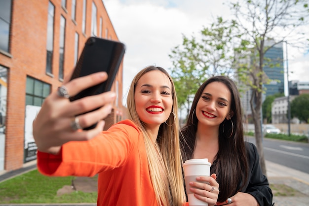 Retrato de dois jovens amigos tirando uma selfie com o celular na rua. Conceitos de estilo de vida e amizade.