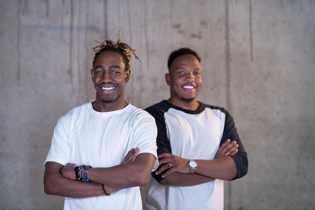 retrato de dois jovens empresários casuais afro-americanos sorridentes em frente a uma parede de concreto no novo escritório de inicialização