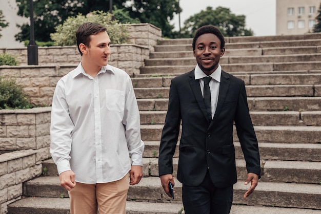 Retrato de dois jovens empresários confiantes descendo as escadas e conversando