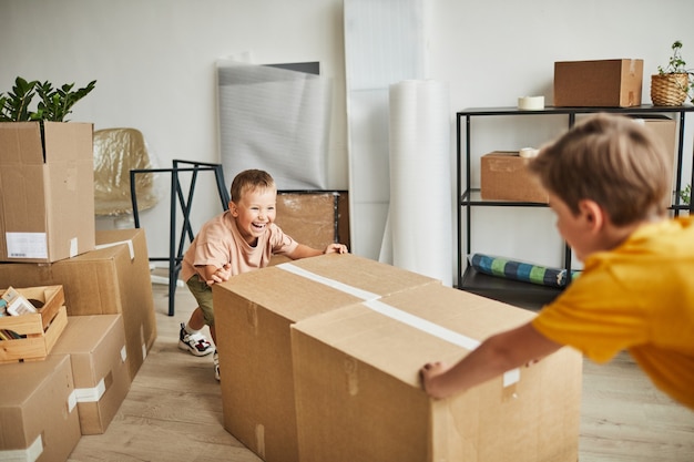 Retrato de dois meninos felizes movendo caixas e brincando enquanto a família se muda para um novo espaço de cópia da casa