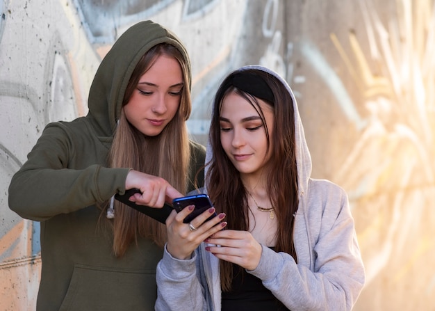 Retrato, de, dois, mulheres adolescentes, olhando um ao outro, e, segurando, telefones móveis